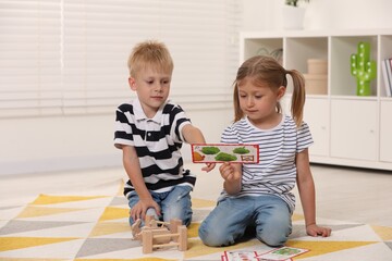 Wall Mural - Little boy and girl playing with set of wooden animals indoors. Children's toys