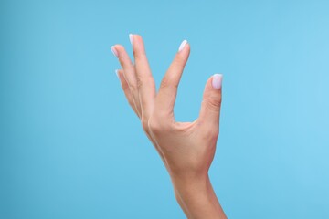 Wall Mural - Woman holding something in hand on light blue background, closeup. Space for text