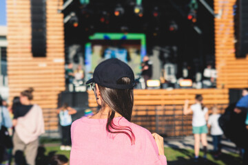 Crowded open air festival concert with scene lights with musicians band on stage at the venue, rock show performance, with concert-goers attendees, audience on dance floor during summer festival