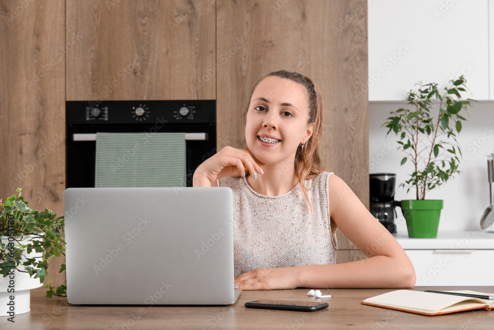 Female freelancer working with laptop at table in kitchen