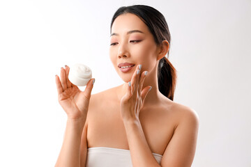 Poster - Beautiful Asian woman with cosmetic cream on white background