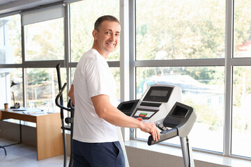 Sticker - Sporty mature man training on treadmill at home