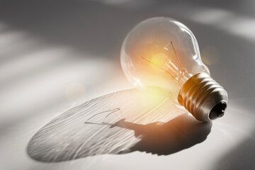 Wall Mural - Glowing bulb on the brown wooden background. Light bulb ideas concept. Close up glowing bulb isolated on white background.