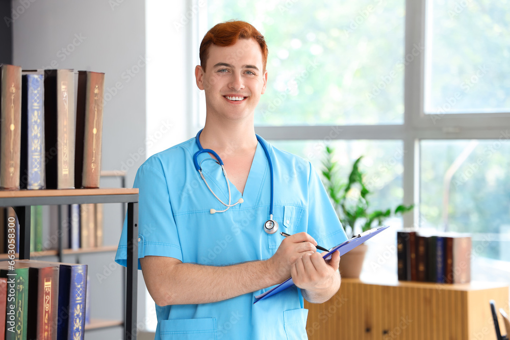 Male medical student with clipboard in library