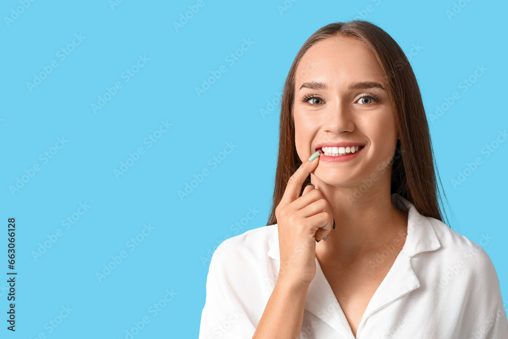 Smiling young woman with healthy teeth on blue background