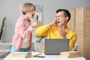 Wall Mural - Young man stressed of his noisy little son singing at home