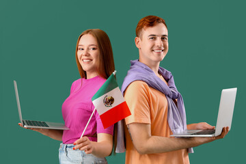 Wall Mural - Young couple with Mexican flag and laptops on green background