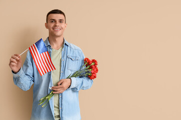 Wall Mural - Young man with USA flag and flowers on beige background. Veterans Day celebration