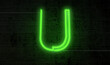 Bright neon letter 'U' on a background of black bricks, projecting an electrifying aura.