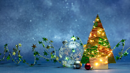 Canvas Print - christmas tree decorated by glowing holiday lights with new year balls on blue background.