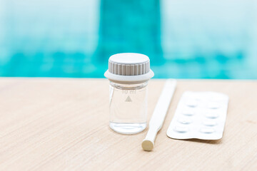 Sticker - Swimming pool water in glass vials with tablet reagents and stirring rod on swimming pool edge, water analysis tools, sample tube with pool water