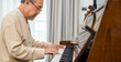 © sorapop - Happy relaxation Asian senior retirement man with eyeglasses learn to play piano at home, elderly old man playing music on piano in living room, lifestyle life after retirement, Close up hands