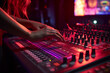 Close-up of woman's hand adjusting buttons on audio mixer in recording studio in neon lighting