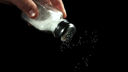 Poster - Salt falls from a salt shaker on a black background. Filmed on a high-speed camera at 1000 fps. High quality FullHD footage