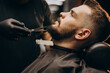© Petro - Handsome man cutting beard at a barber shop salon