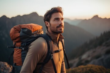 Wall Mural - Handsome young man with backpack hiking in the mountains at sunset