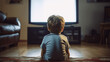 Rear view of a boy sitting on the floor and watching tv