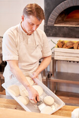 Wall Mural - Dough for pizza, the chef rolls out the blanks. Closeup hand of chef baker in uniform white apron cook pizza at kitchen