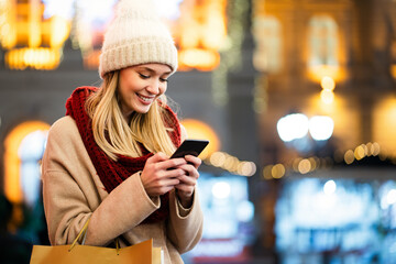 Wall Mural - portrait of smiling woman using mobile phone in the city at winter. people communication concept