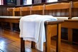 white prayer shawl draped over an empty synagogue chair