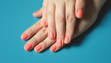 Female hands with pink manicure on blue background close-up.