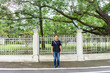 © Surachetsh - Asian Black T-Shirt is standing in front of white vintage fence beside the road in the afternoon time.