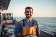 Front view of mid adult Caucasian man in t-shirt and bib overalls smiling at camera while holding catch from Mediterranean Sea in early morning
