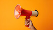 Close up hand holding megaphone, marketing and sales, orange background.