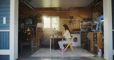 Poster - Hispanic Female Software Engineer Programming On Laptop Computer In Garage At Home. Focused Young Woman Working On Innovative Online Service Startup Company, Coding. Digital Entrepreneur Concept.