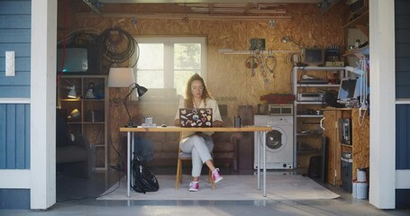 Poster - Hispanic Female Software Engineer Coding On Laptop Computer In Garage At Home. Focused Young Woman Working On Innovative Online Service Startup Company. Entrepreneur Starting Business Concept.