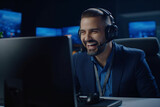 Fototapeta Tulipany - Happy Confident Technical Customer Support Specialist Having a Headset Call while Working on a Computer in a Dark Monitoring and Control Room Filled with Colleagues and Display Screens