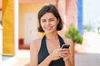 © luismolinero - Young pretty Bulgarian woman at outdoors sending a message with the mobile