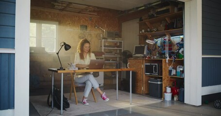 Poster - Hispanic Female Programmer Coding On Laptop Computer In Garage At Home. Young Woman Working On Innovative Software As A Service Startup For Business. Digital Entrepreneur Starting Company Concept.