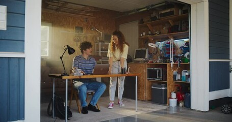 Poster - Caucasian Male Software Developer And Hispanic Female User Interface Designer Talking And Using Laptop Computer in Garage At Home. Diverse Young Startup Founders Working On Innovative Online Service.
