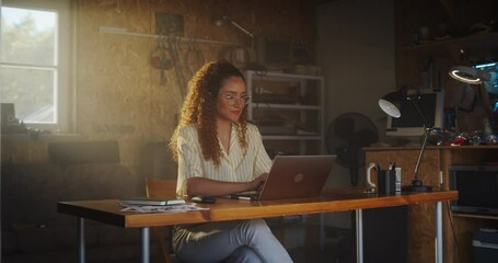 Poster - Hispanic Female Programmer Writing Code On Laptop Computer In Garage At Home. Woman Working On Innovative Software As A Service Startup For Business. Digital Entrepreneur Starting Company Concept.