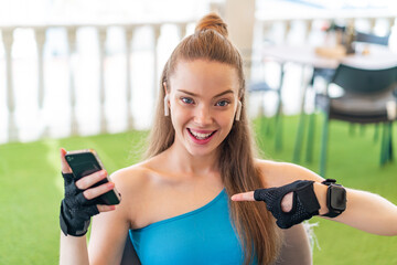 Canvas Print - Young pretty sport girl using mobile phone at outdoors with surprise facial expression