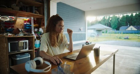 Poster - Young Hispanic Female Software Engineer Programming On Laptop Computer In Opened Garage. Woman Running A Startup With Innovative SaaS Solution For Businesses. Developer Writing Code, Optimizing System