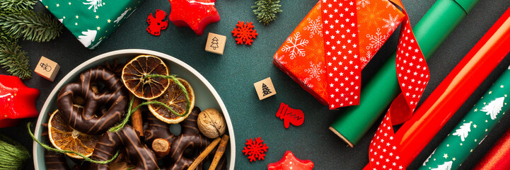 Wall Mural - Preparing for the holiday, wrapping gifts under the Christmas tree in red and green paper, Merry Christmas and New Year banner, plate with cookies and dry tangerine slices