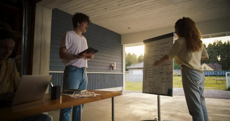 Fototapete - Diverse Team Of Young Entrepreneurs Having A Meeting In Home Garage. Hispanic Female Manager Using Whiteboard To Outline Business Plan For Tech Startup. Two Male Co-Founders Using Laptop And Tablet.