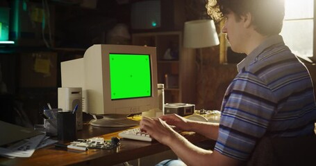 Poster - Zoom In Shot Of Caucasian Male Engineering Student Writing Thesis On Old Computer With Green Screen Chromakey On Display In Retro Garage. Engineer Focused On Project For Tech University In Nineties.