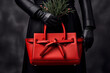 © Glittering Humanity - A festive fashionista embraces the holiday spirit with a bold red purse, adorned with pine and berries, while her black leather glove adds a touch of elegance to her outdoor ensemble