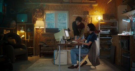 Fototapete - Two Caucasian Male Tech Startup Founders Using Old Desktop Computer In Retro Garage In The Evening. Software Developer And User Experience Designer Starting New Online Service Business In Nineties.