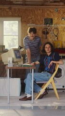 Leinwandbilder - Vertical Screen: Two Caucasian Male Tech Startup Founders Using Old Desktop Computer In Retro Garage, Looking At Camera And Smiling. Programmer And UX Designer Starting Internet Business In Nineties.