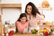 © Prostock-studio - Mother and little daughter using smartphone while cooking in kitchen