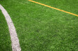 Artificial plastic green football grass background with white and yellow painted line.