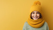 © Alice - Cute little smiling girl in winter clothes, knitted hat and scarf isolated on yellow color background with copy space. Happy little female child