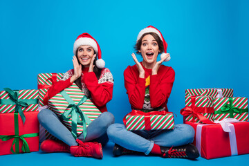 Poster - Full length photo of impressed funky ladies santa helpers dressed print sweaters preparing xmas presents isolated blue color background