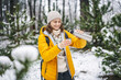 Young woman with a thermos in a snowy forest. Winter walking and healthy lifestyle