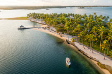 Aerial View Of A Small Motorboat Moored Along The Coastline With Palm Trees And Beach Umbrellas Near A Resort In Poste De Flacq, Flacq District, Mauritius.