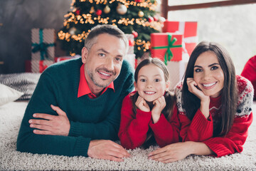 Poster - Full size portrait of lovely friendly family small daughter cheerful parents lying carpet floor newyear tree illumination indoors